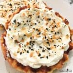 Close view of a golden chaffle with cream cheese and sprinkled with everything seasoning.