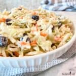 Side view of coleslaw with dried cranberries in a white bowl and ready to be served.