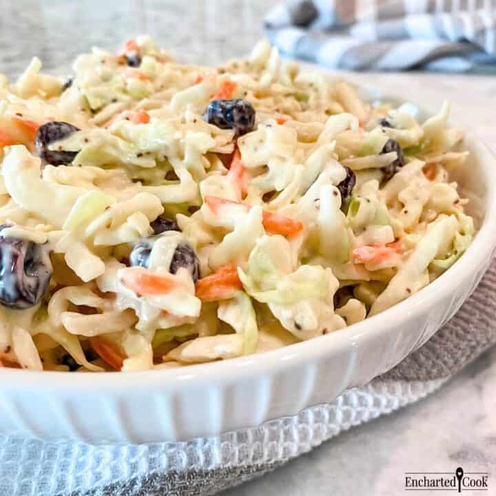 Side view of coleslaw with dried cranberries in a white bowl and ready to be served.