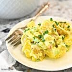 A serving of Classic Potato Salad on a white plate with a fork.
