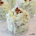 Pale green Pistachio Fluff Salad in a small glass cups topped with chopped pecans.
