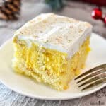 A slice of yellow eggnog cake on a white plate with a fork.