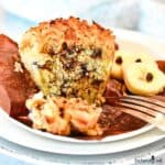 Banana Chocolate Chip Muffin with unwrapped brown parchment paper on a plate with a fork.