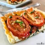 A slice of Tomato and Goat Cheese Tart on a plate with a fork.