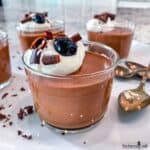 Chocolate Mousse in glass cups topped with whipped cream, chocolate shavings, and a cocktail cherry.