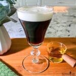 Irish coffee in a traditional elegant glass cup with a decorative stem.