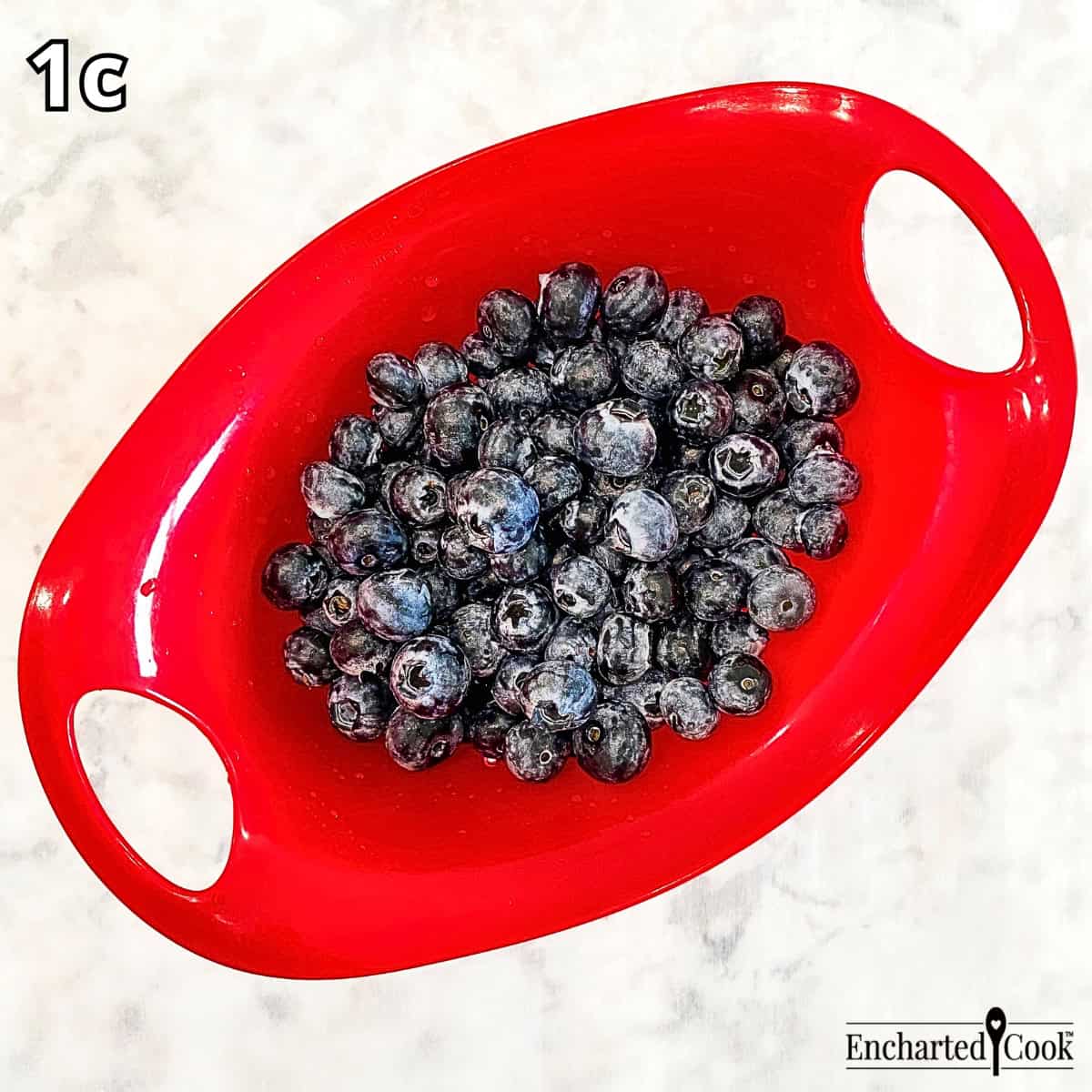 Process Photo 1c - Rinsing the blueberries in a small red colander.