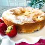 Strawberry French Butter Cake on a white fluted plate garnished with whole strawberries.