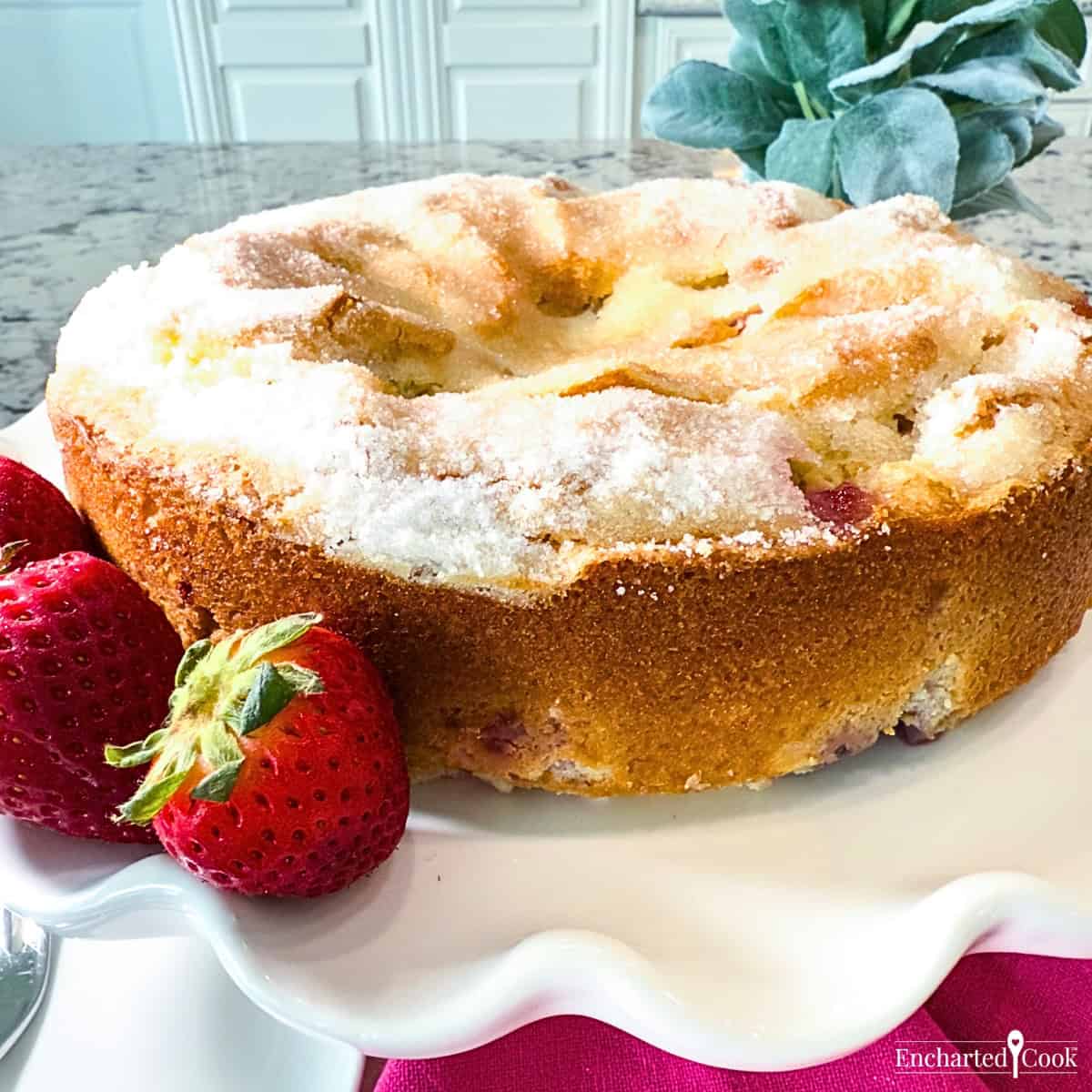 Strawberry French Butter Cake on a white fluted plate garnished with whole strawberries.