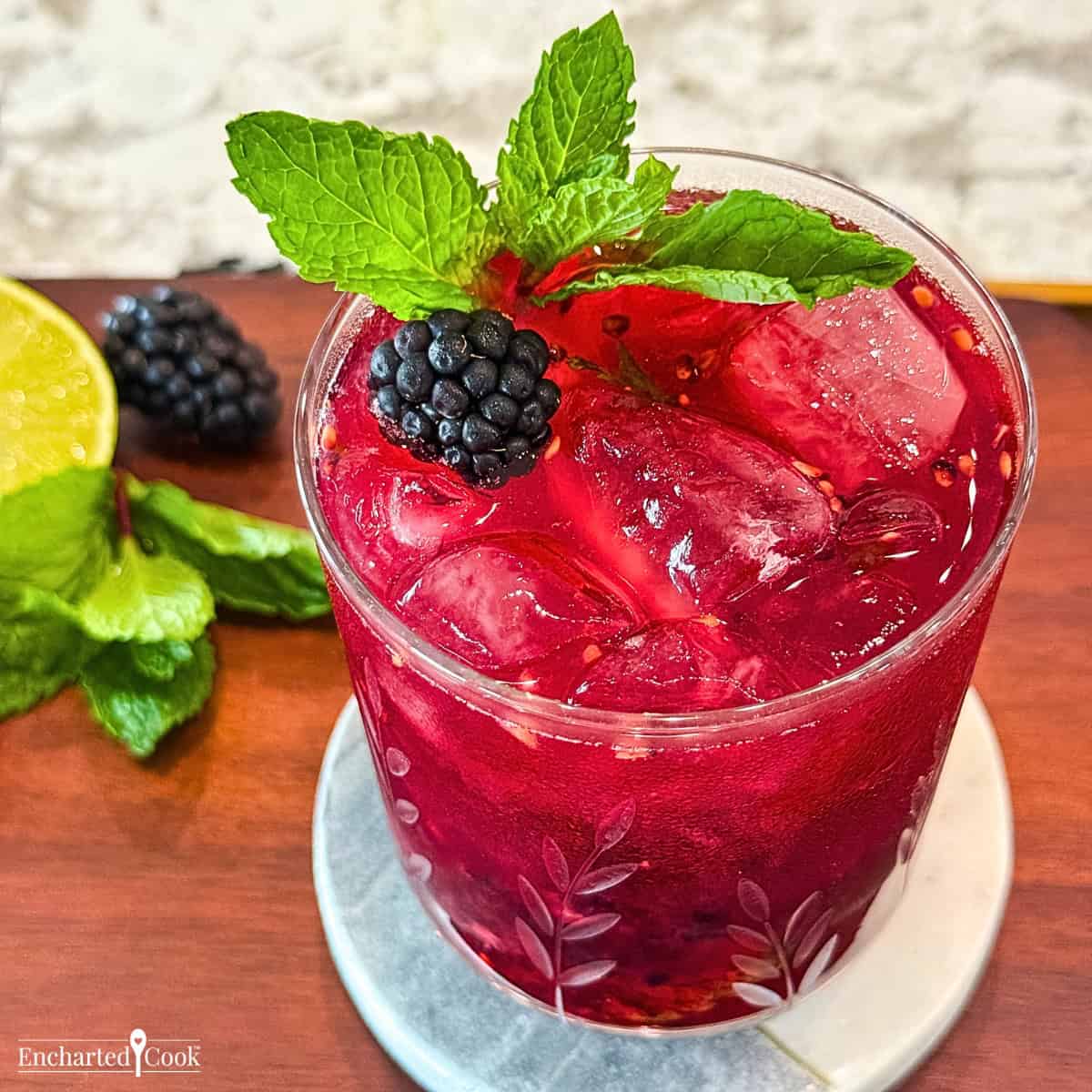 A blackberry and mint cocktail with lime and mint garnish.