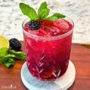 A blackberry and mint cocktail with lime and mint garnish.