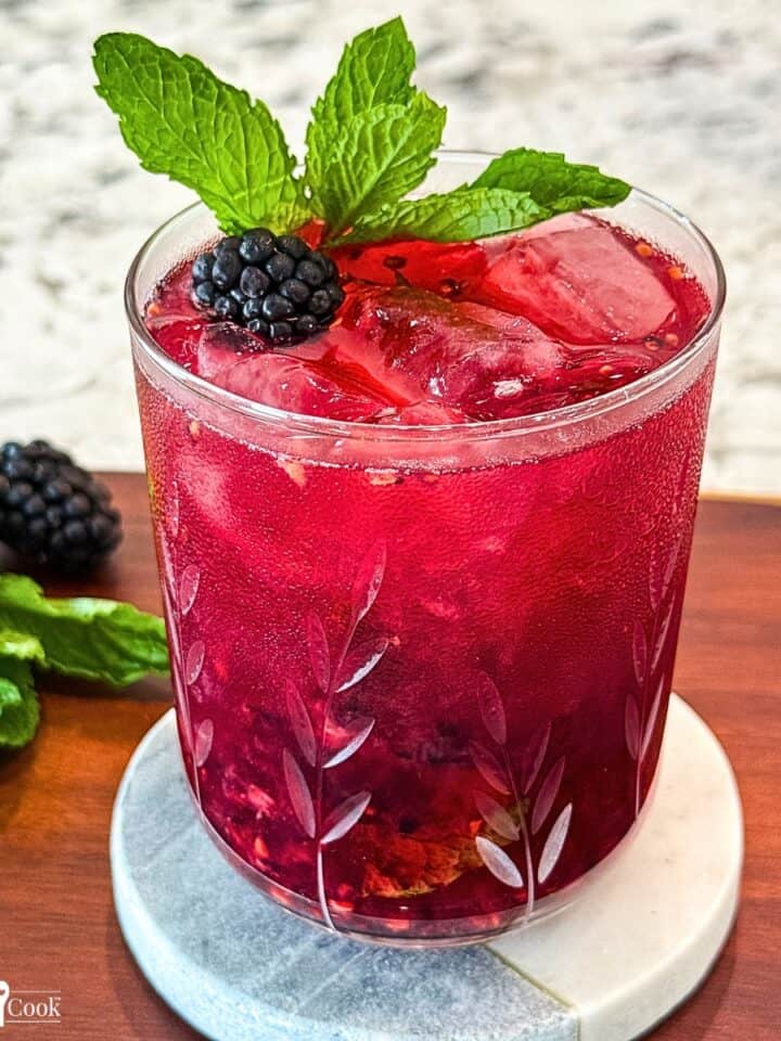 A blackberry and mint cocktail with lime and mint garnish.