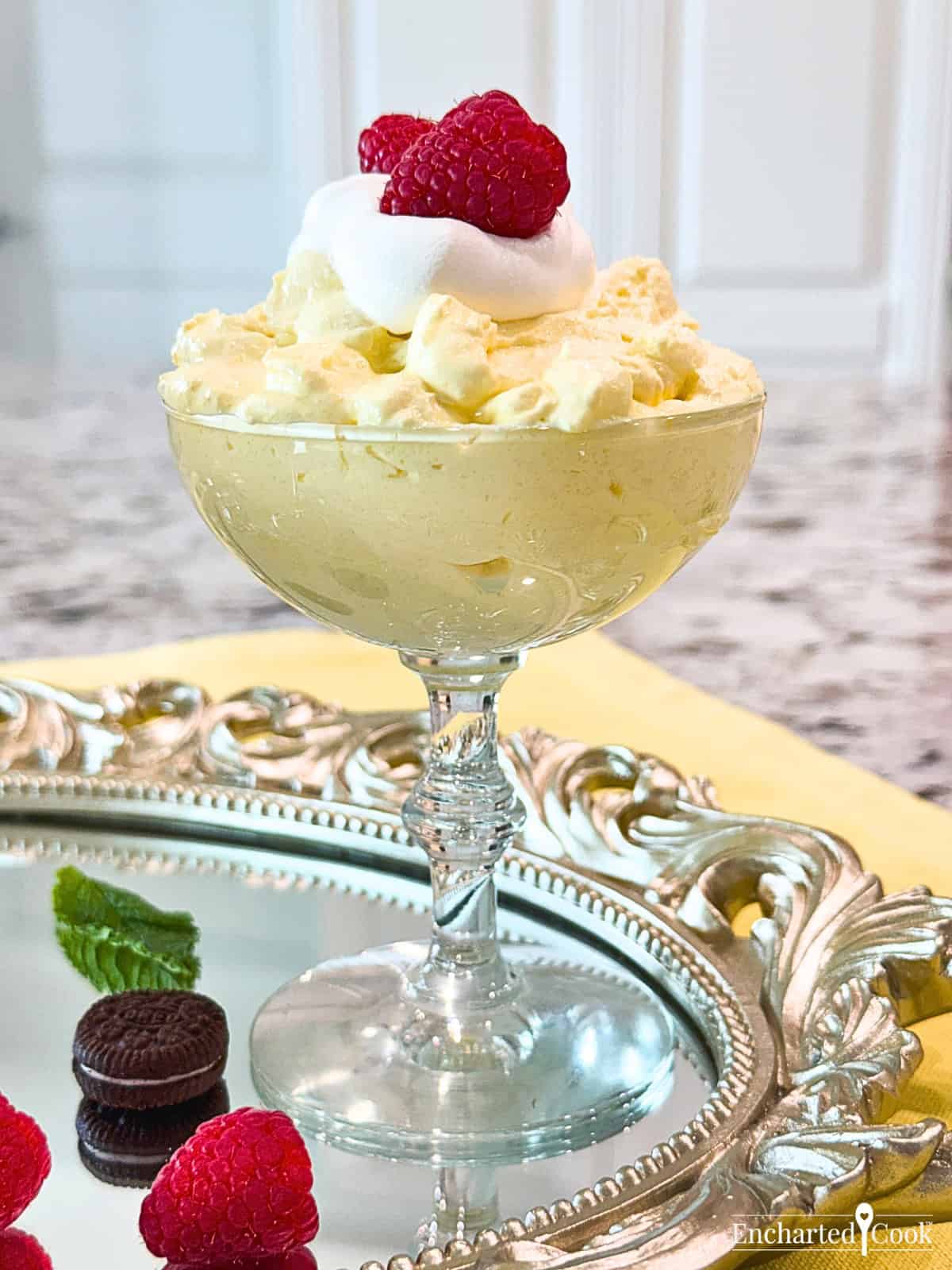 Lemon Cream Fluff in a dessert glass garnished with fresh raspberries.