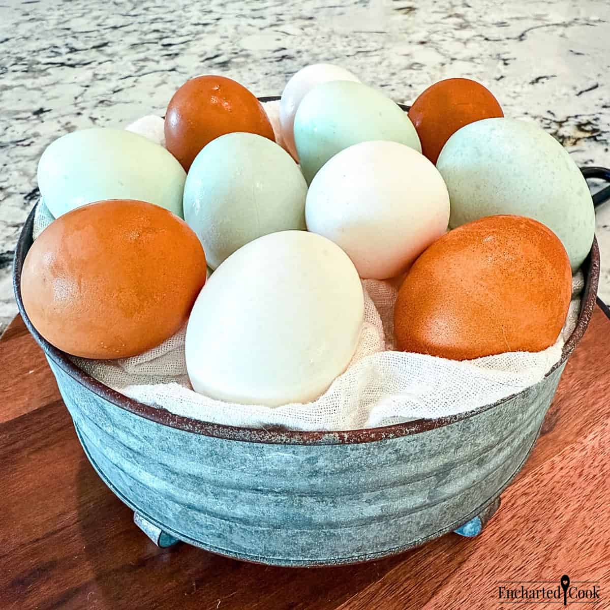 Large eggs in a variety of colors in a metal bowl.