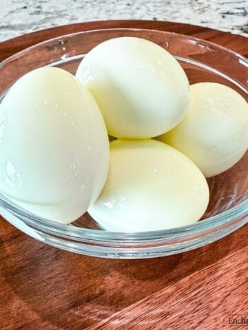 Perfect hard boiled eggs with the eggshell removed and are in a glass bowl.