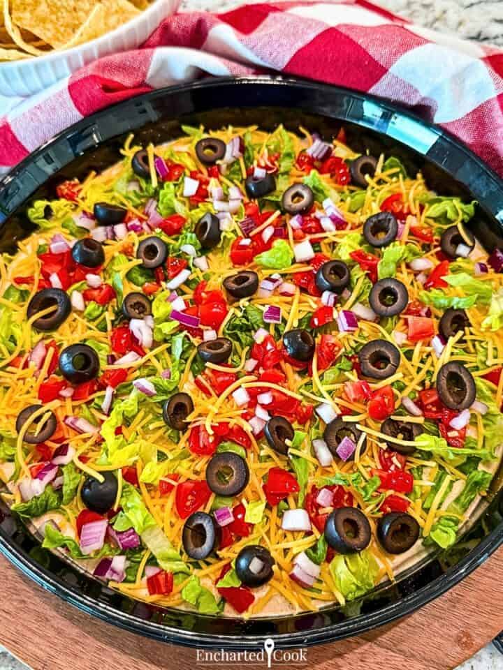 Taco Dip with all the fixings in a black ceramic dish.