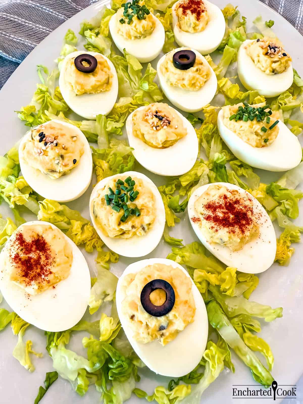 Deviled Eggs with various garnishes on a white platter with lettuce.