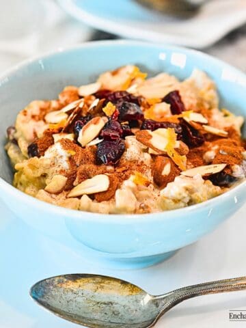 Creamy Good Morning Oatmeal in a blue bowl topped with cinnamon, dried cranberries, and sliced almonds.