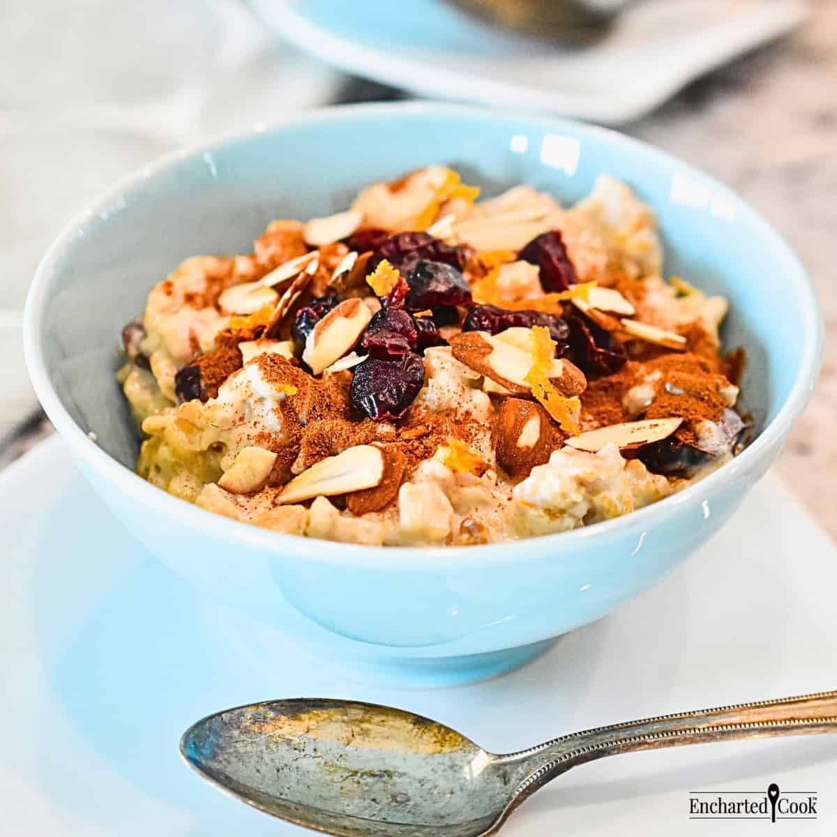 Creamy Good Morning Oatmeal in a blue bowl topped with cinnamon, dried cranberries, and sliced almonds.