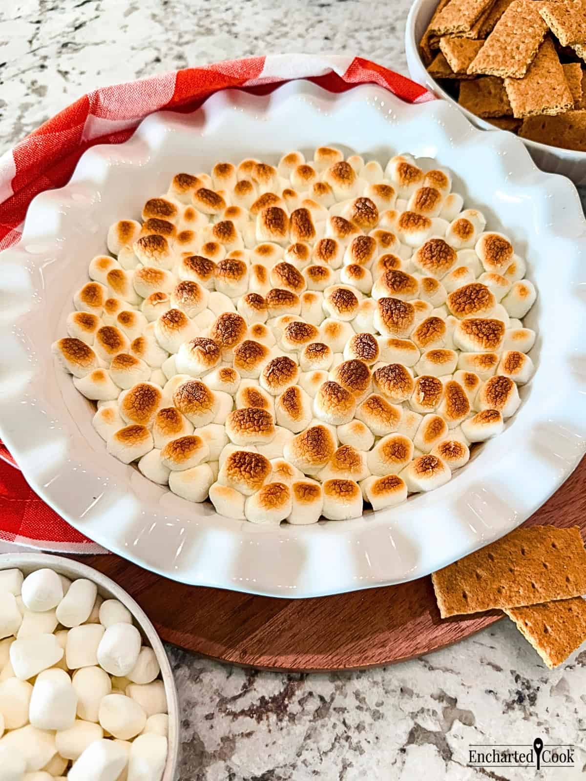 Smores Party Dip topped with toasted mini marshmallows in a white ceramic pie plate.