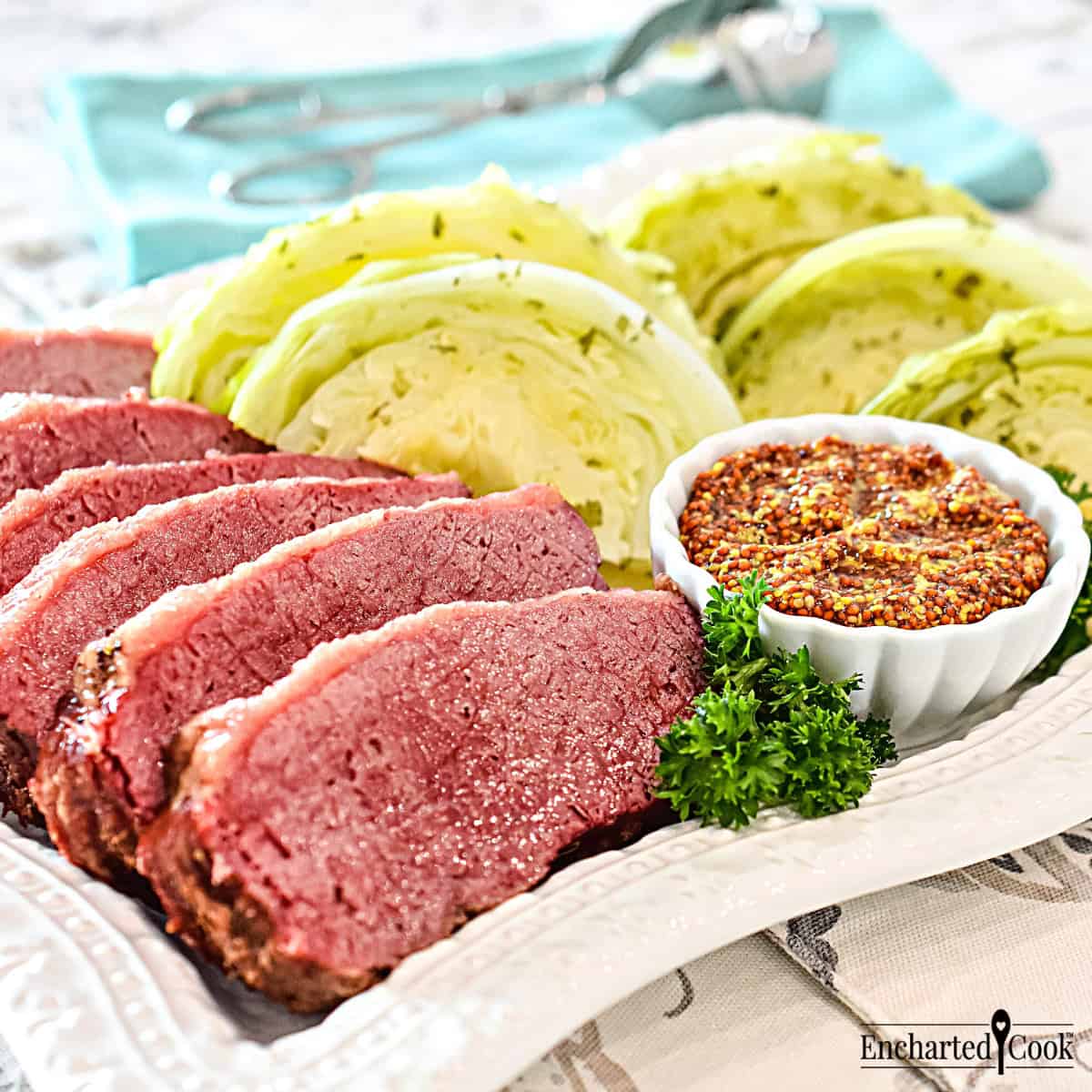 Corned beef and green cabbage on a white platter with a dish of whole grain mustard.