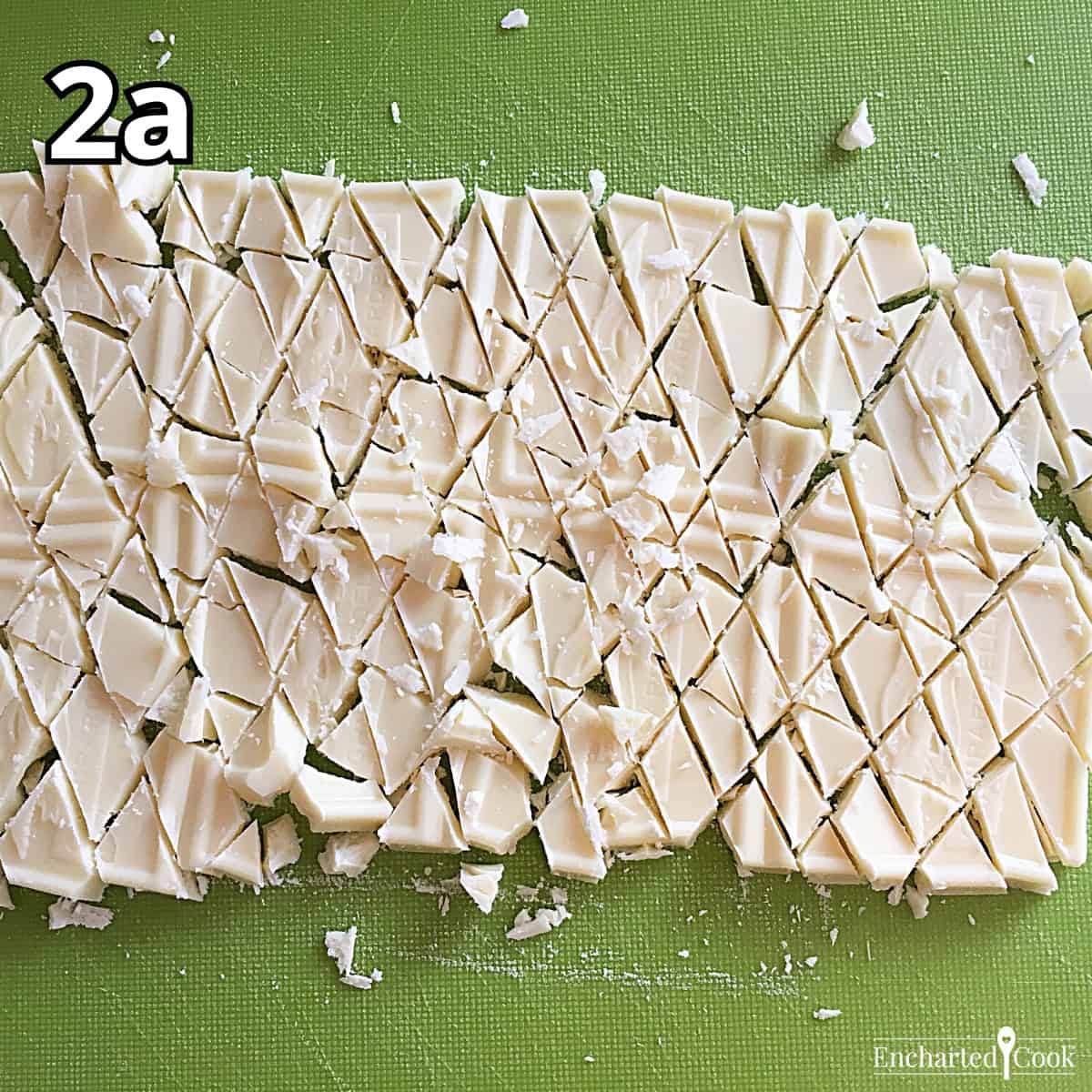 Process Photo 2a - Finely chopped white chocolate on a green cutting board.