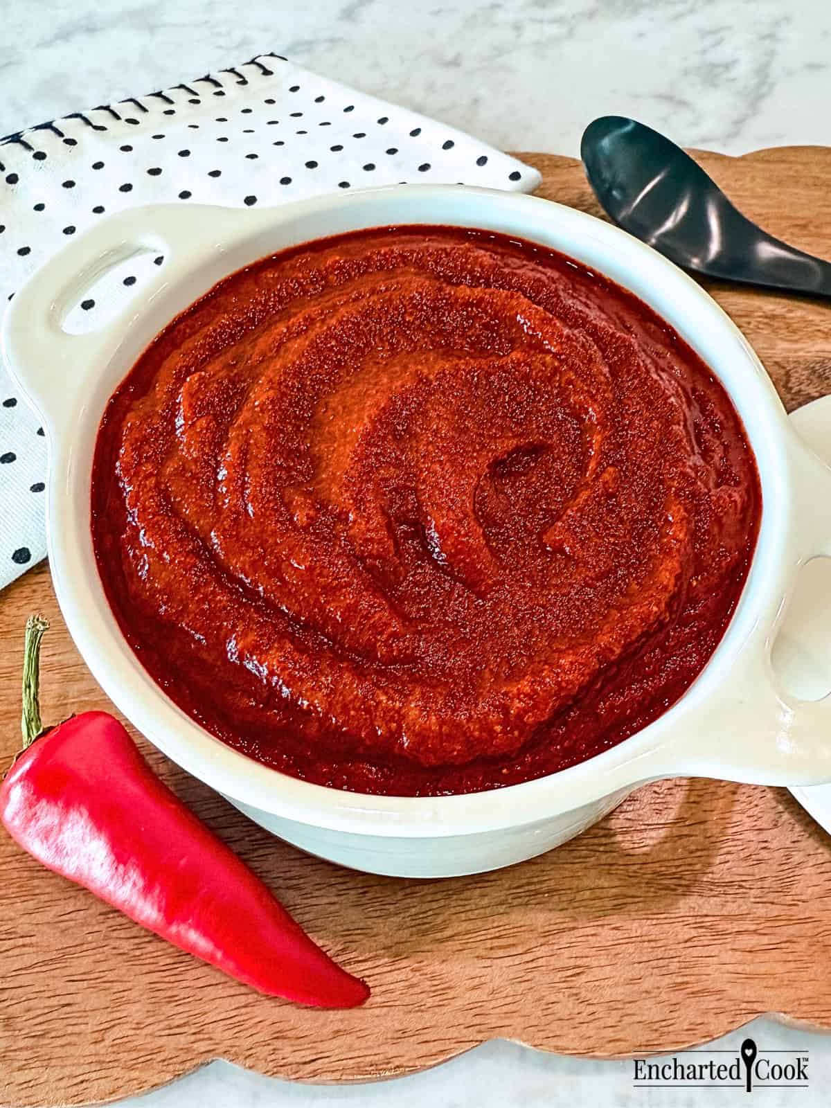 Red Enchilada Sauce in a white dish on a wooden board.