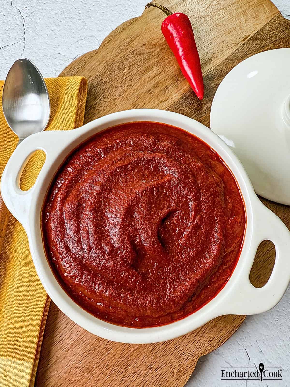 Red Enchilada Sauce in a white dish on a wooden board.