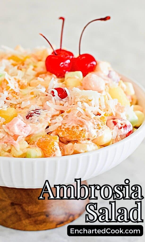 Creamy Traditional Ambrosia Fruit Salad in a white bowl garnished with maraschino cherries with text overlays.