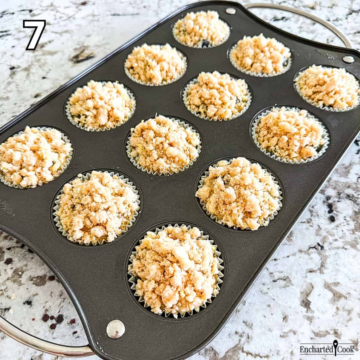 Process Photo 7 - Blueberry muffin batter is evenly divided between the lined muffin wells and topped with the streusel crumb.