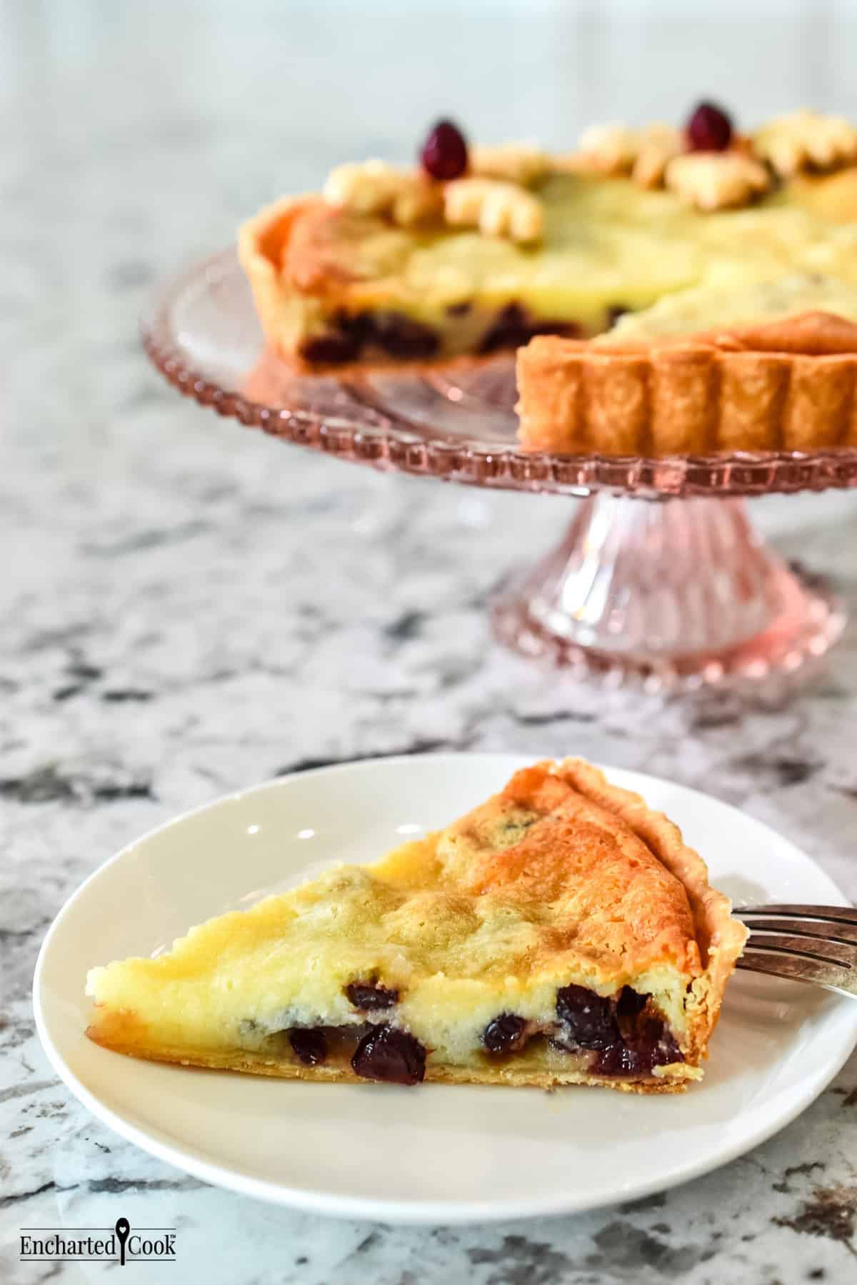 Cranberry Sugar Pie on a pink stand and a slice on a white plate.