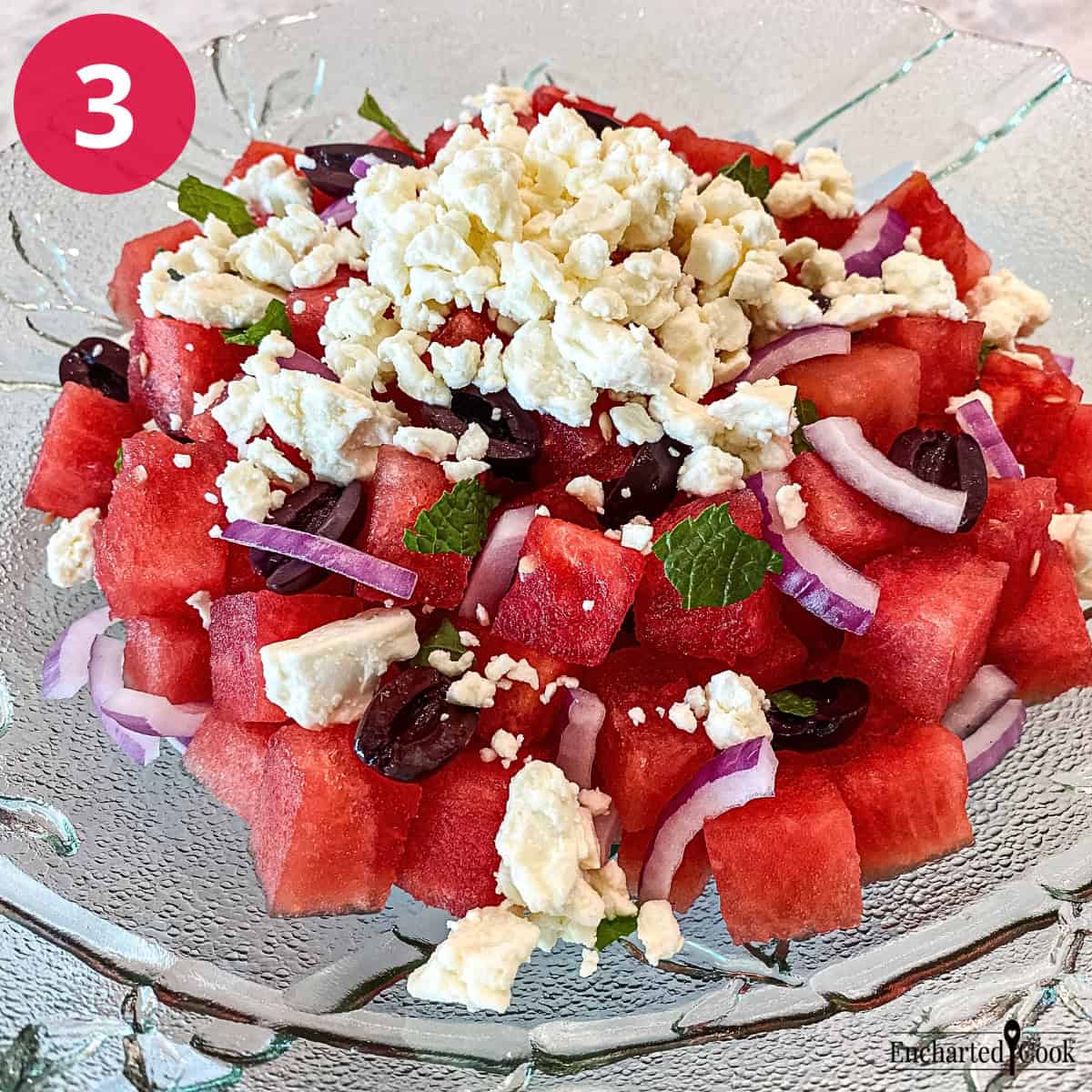 Process Photo 3 - Topping the salad with feta, black olives, and mint leaves.
