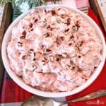 Pink Cranberry Fluff garnished with chopped pecans in a white bowl.