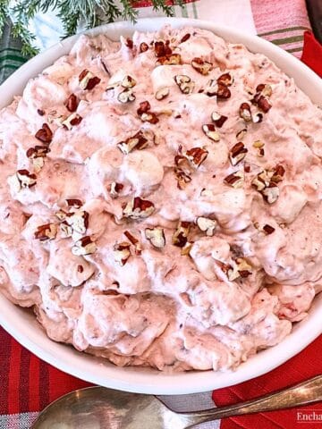 Pink Cranberry Fluff garnished with chopped pecans in a white bowl.