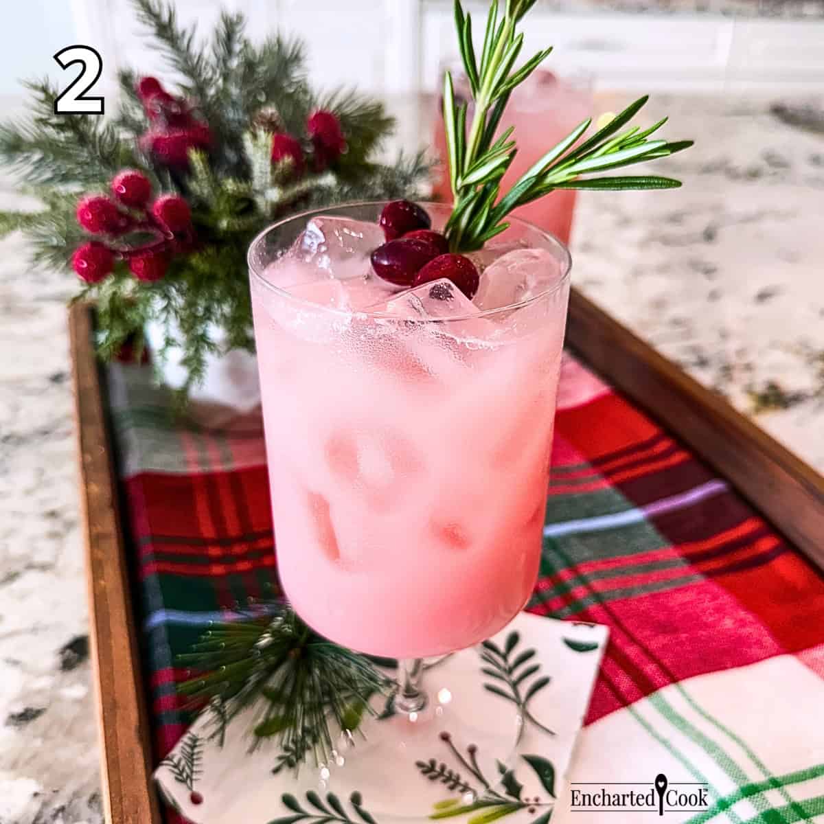 Process Photo 2 - The mixed drink poured over ice in a glass and garnished with sprigs of rosemary and fresh cranberries.
