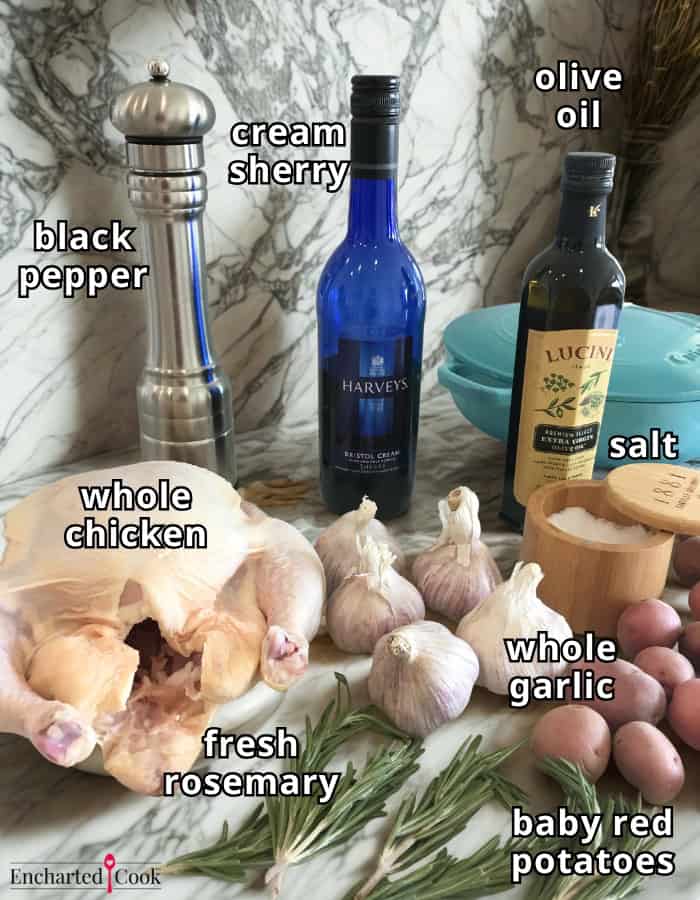 Roasted Chicken with Potatoes and Garlic ingredients, labeled, clockwise from top left: black pepper, cream sherry, olive oil, salt, whole garlic, baby red potatoes, fresh rosemary, and a whole chicken.