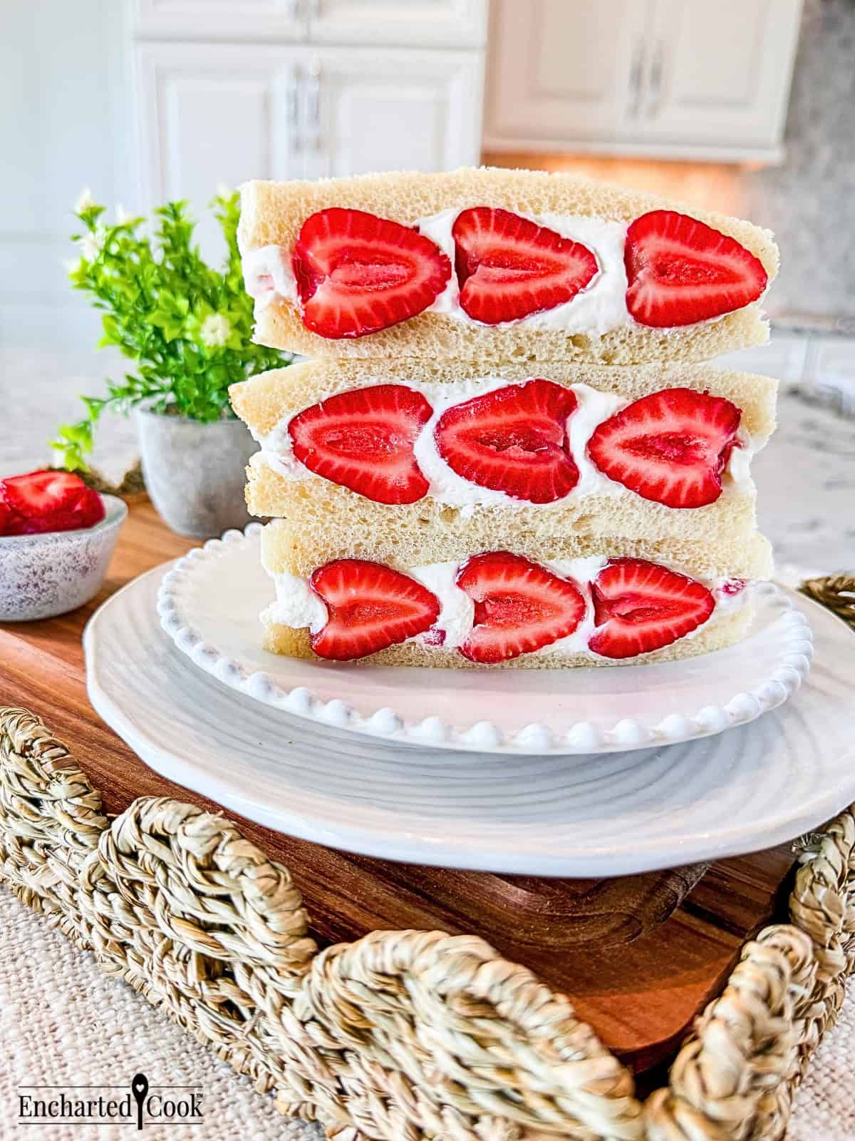 Three Strawberry Sando on a white plate, sitting on a wooden tray with wicker trim.