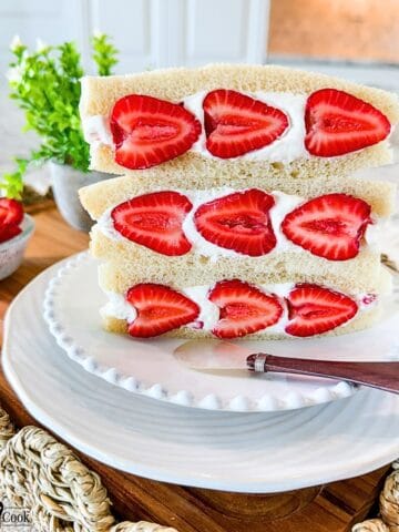 Three Strawberry Sando on a white plate with a spreader knife for decor.