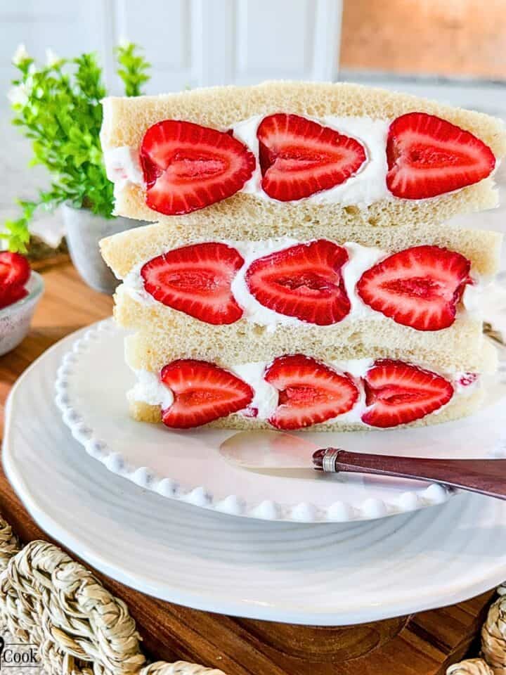 Three Strawberry Sando on a white plate with a spreader knife for decor.