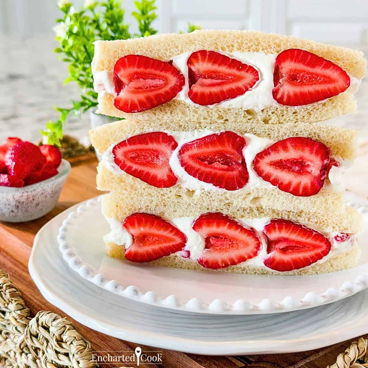 Three Strawberry Sando on a white plate, sitting on a wooden tray with wicker trim.