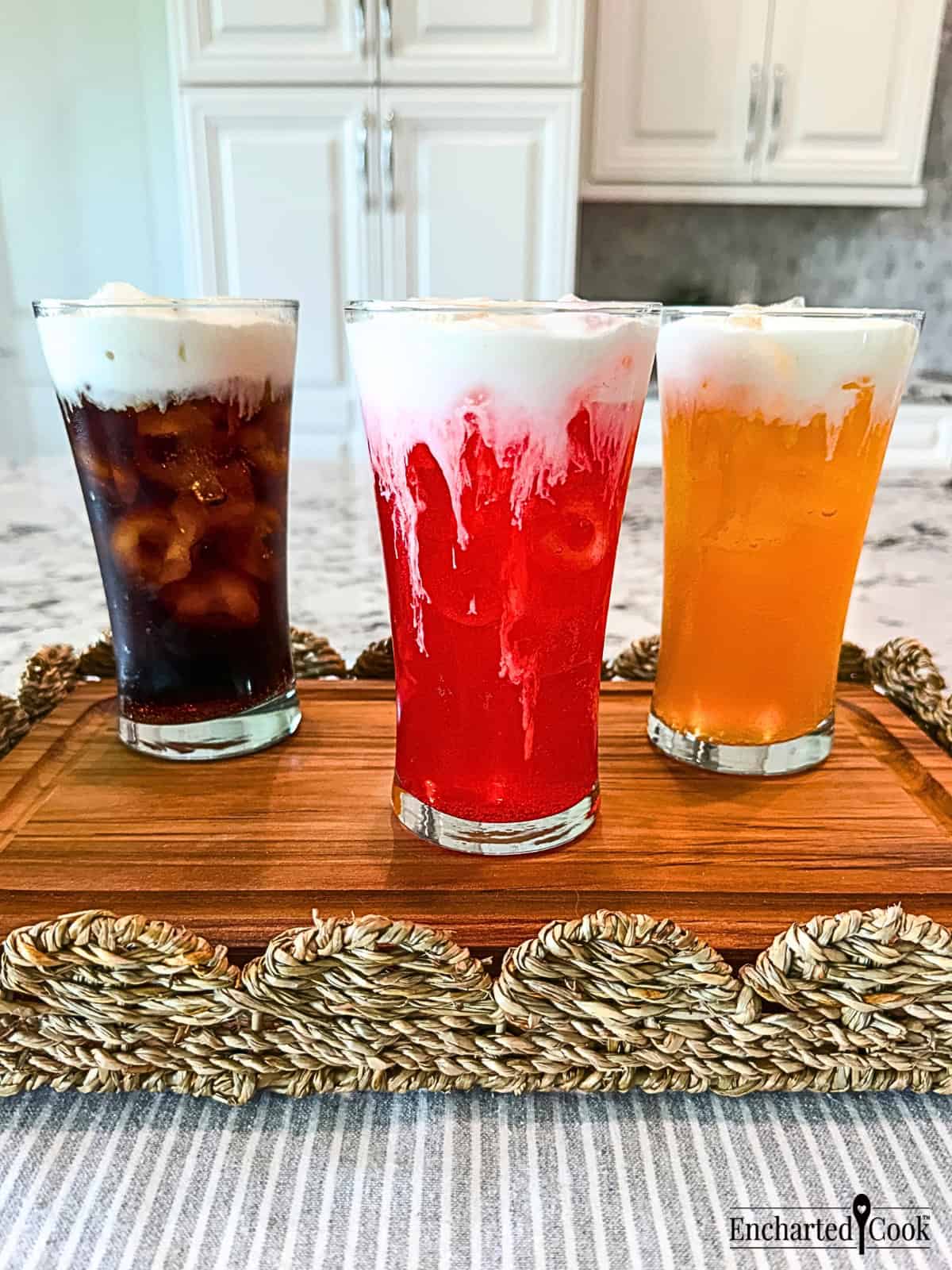 Three iced sodas, cola, fruit punch, and orange, in tall glasses are topped with Vanilla Sweet Cream Cold Foam.