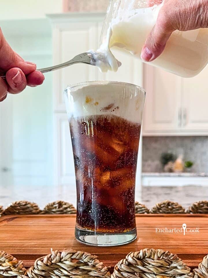 Cold foam is poured over the back of a spoon, so it gently floats on top of an iced beverage.