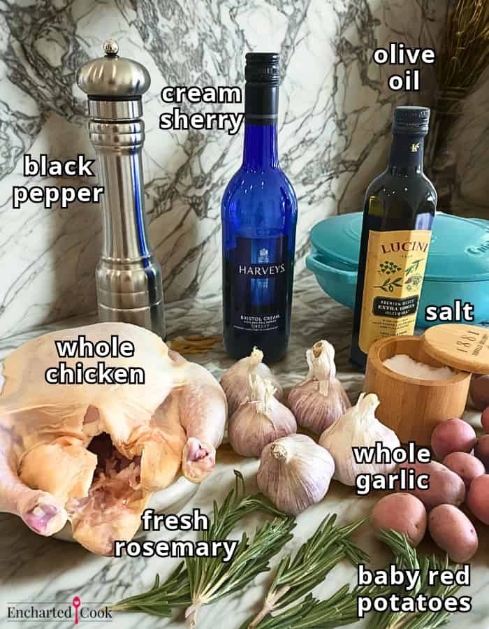 Roasted Chicken with Potatoes and Garlic ingredients, labeled, clockwise from top left: black pepper, cream sherry, olive oil, salt, whole garlic, baby red potatoes, fresh rosemary, and a whole chicken.